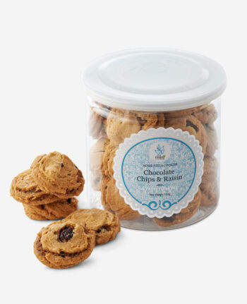 Jar of chocolate chip and raisin cookies with a blue decorative label, several cookies spilled outside the jar on a white background